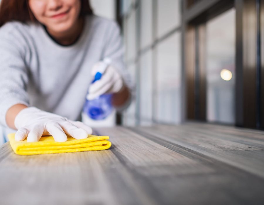 A young woman wearing protective glove cleaning the table for housework concept